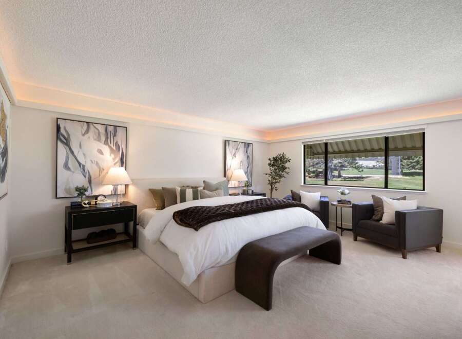 Experience luxury in this master suite, featuring a plush king-sized bed adorned with designer linens and a rich brown throw.