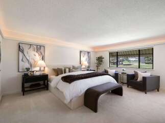 Experience luxury in this master suite, featuring a plush king-sized bed adorned with designer linens and a rich brown throw.