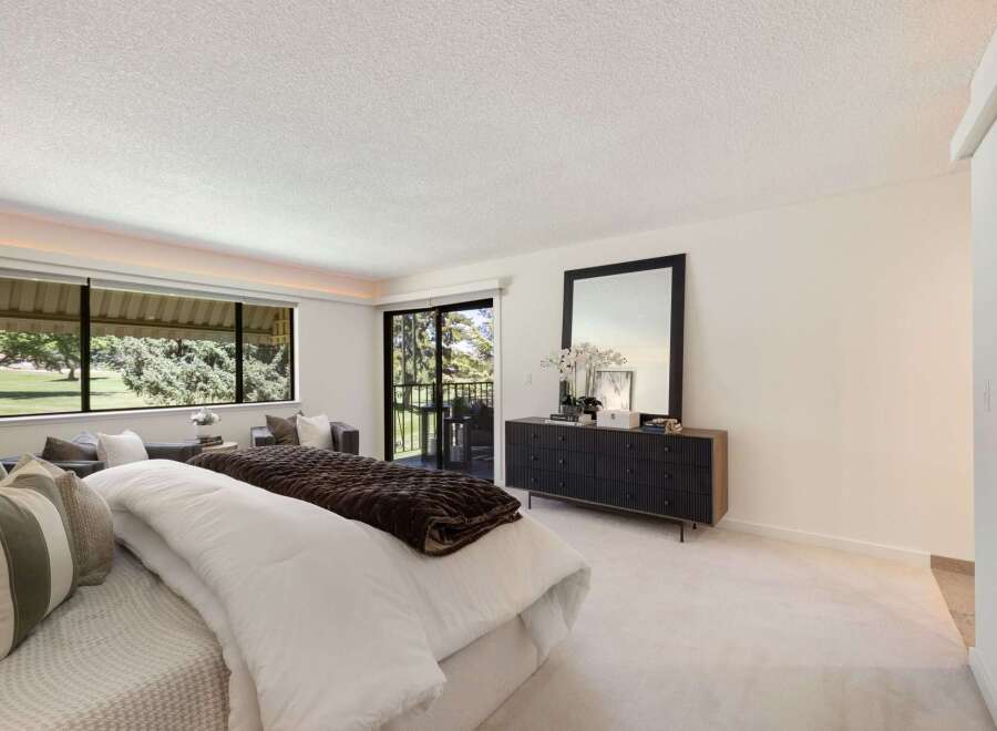 Experience luxurious living in this spacious bedroom featuring a large bed with plush bedding and a cozy seating area.