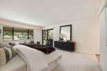 Experience luxurious living in this spacious bedroom featuring a large bed with plush bedding and a cozy seating area.