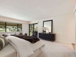 Experience luxurious living in this spacious bedroom featuring a large bed with plush bedding and a cozy seating area.
