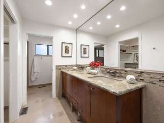 This spacious bathroom features a double vanity with granite countertops and a modern mosaic tile backsplash.