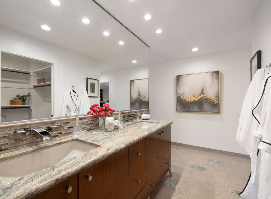 Experience luxury in this stunning bathroom featuring a dual vanity with granite countertops and modern waterfall faucets.