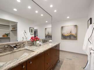 Experience luxury in this stunning bathroom featuring a dual vanity with granite countertops and modern waterfall faucets.