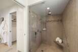Step into this luxurious bathroom featuring a spacious glass-enclosed shower with multiple shower heads and a built-in bench.