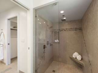 Step into this luxurious bathroom featuring a spacious glass-enclosed shower with multiple shower heads and a built-in bench.