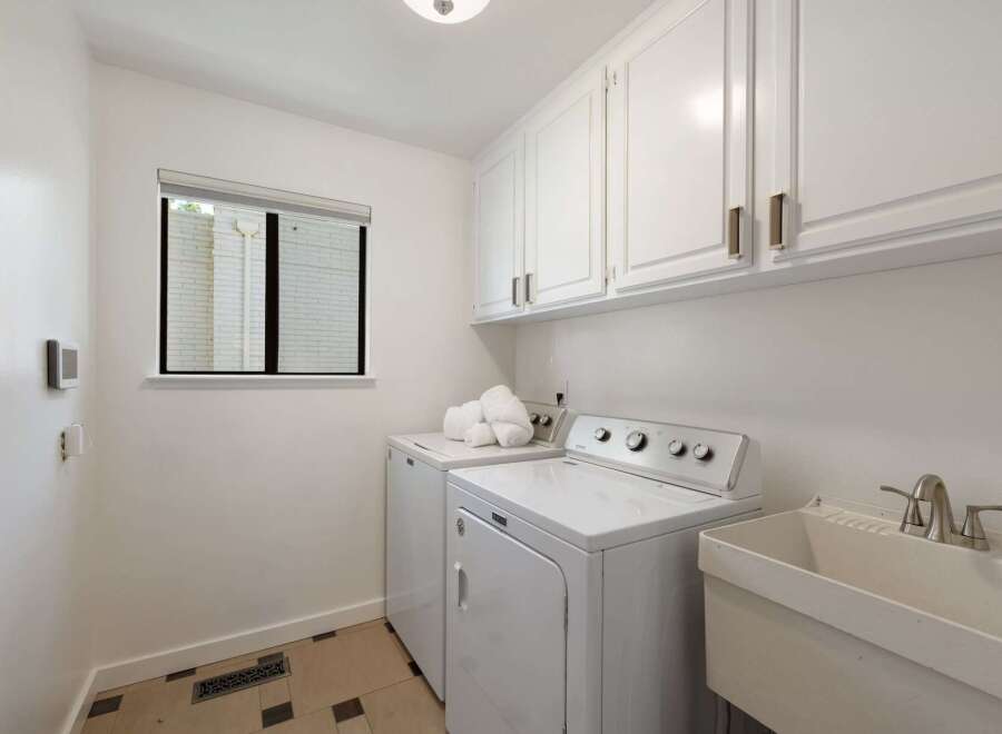 This laundry room features a white Maytag washer and dryer set, complemented by ample white cabinetry for storage.