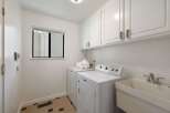 This laundry room features a white Maytag washer and dryer set, complemented by ample white cabinetry for storage.