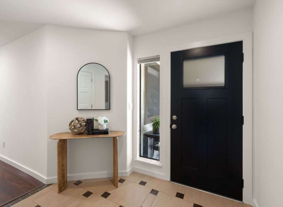 Step into this welcoming entryway featuring a sleek black front door with a frosted glass window, offering both style and privacy.