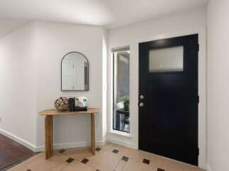 Step into this welcoming entryway featuring a sleek black front door with a frosted glass window, offering both style and privacy.