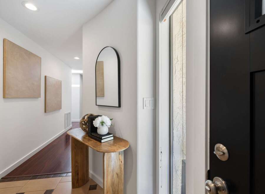 Step into a welcoming entryway featuring a sleek black door and a stylish arched mirror.
