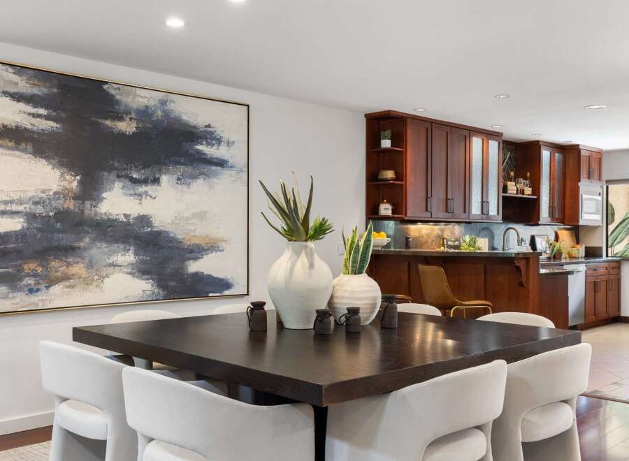 Elevate your dining experience in this sophisticated space, featuring a striking abstract artwork and a dark wood dining table perfect for intimate gatherings.