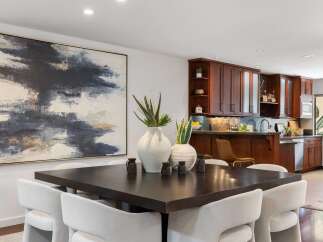 Elevate your dining experience in this sophisticated space, featuring a striking abstract artwork and a dark wood dining table perfect for intimate gatherings.
