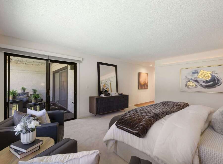 Experience luxurious living in this spacious master suite, featuring a plush king-sized bed adorned with a rich velvet quilt and elegant throw pillows.