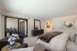 Experience luxurious living in this spacious master suite, featuring a plush king-sized bed adorned with a rich velvet quilt and elegant throw pillows.