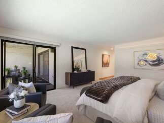 Experience luxurious living in this spacious master suite, featuring a plush king-sized bed adorned with a rich velvet quilt and elegant throw pillows.