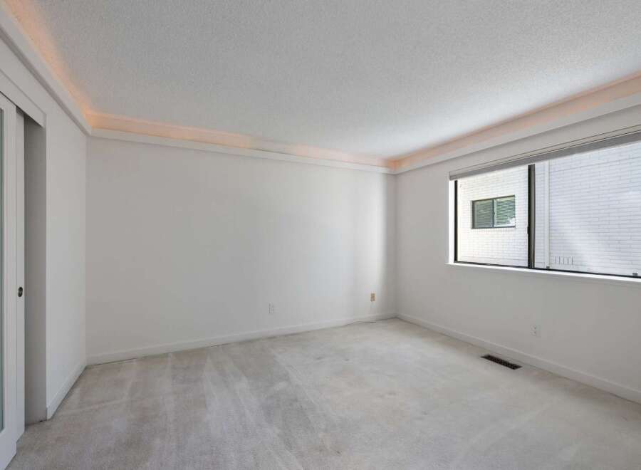 Experience modern living in this spacious room featuring a sleek sliding door and a large window that floods the space with natural light.