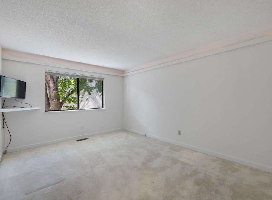 This spacious room features a large window offering a view of lush greenery, perfect for natural light.