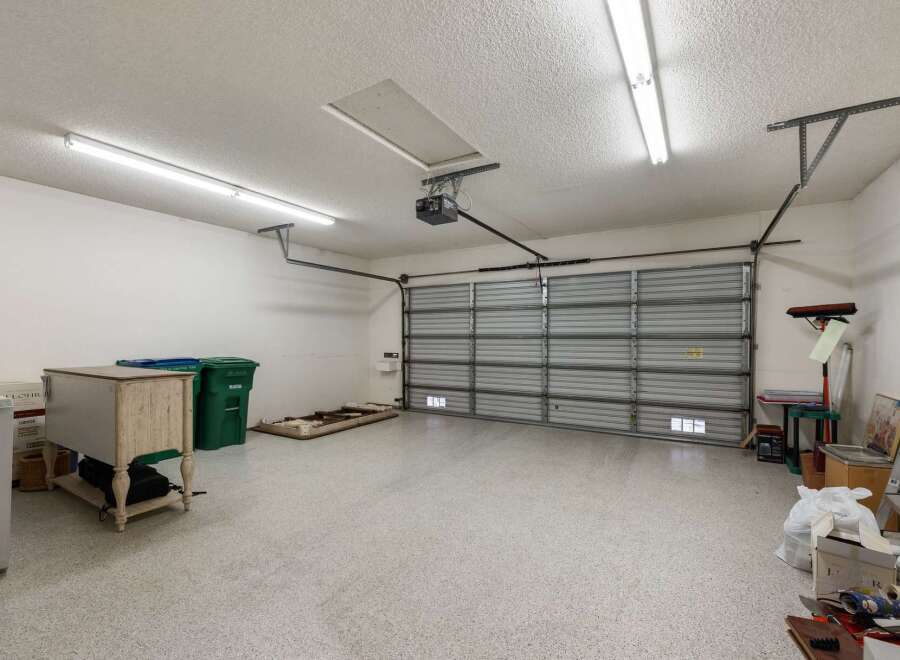 Discover ample storage and organization potential in this spacious garage, featuring a durable epoxy-coated floor and a modern roll-up door.