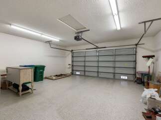 Discover ample storage and organization potential in this spacious garage, featuring a durable epoxy-coated floor and a modern roll-up door.