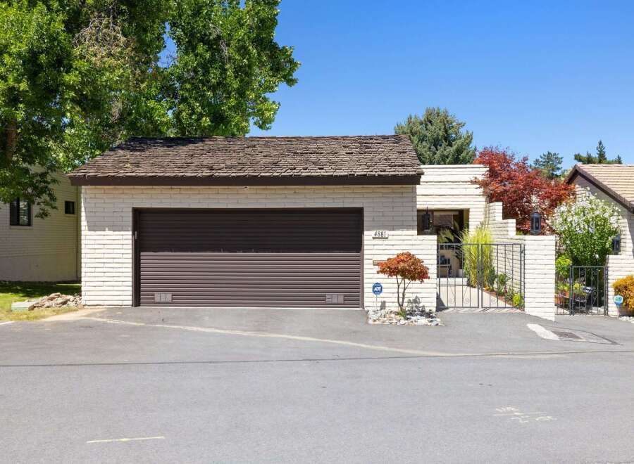 Discover this charming single-family home featuring a welcoming facade with light brick and a dark roll-up garage door.