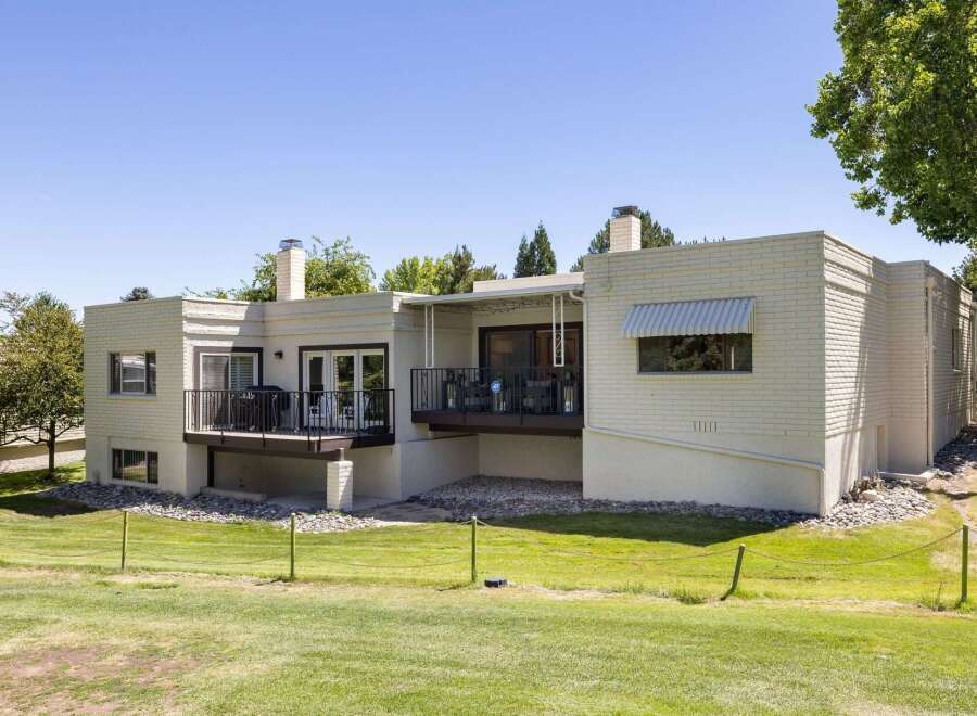 This charming home features a spacious deck perfect for outdoor entertaining, overlooking a lush green lawn and mature trees.