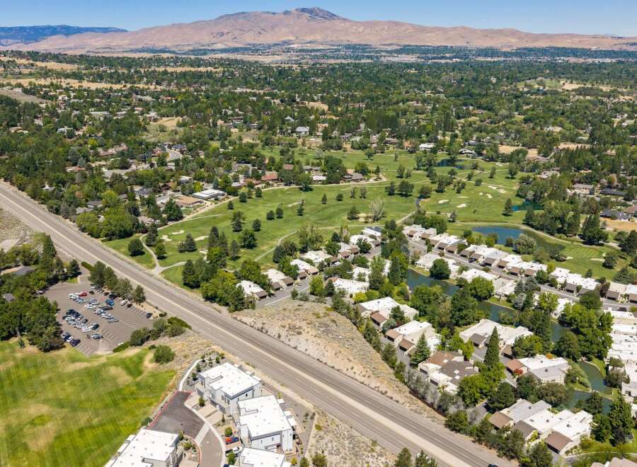 Discover this stunning aerial view showcasing a vibrant community nestled beside a lush golf course and serene water features.