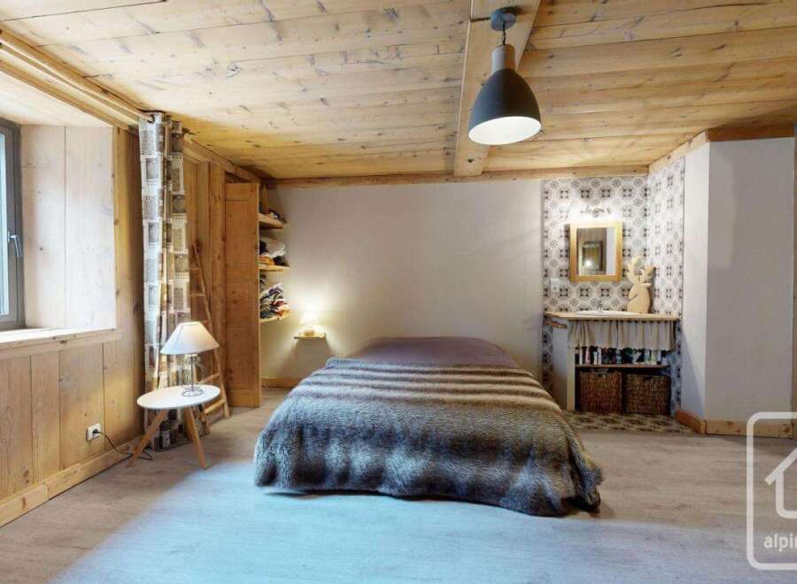 Experience rustic charm in this cozy bedroom featuring a plush, fur-covered bed and warm wooden accents throughout.