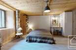 Experience rustic charm in this cozy bedroom featuring a plush, fur-covered bed and warm wooden accents throughout.