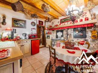 Charming rustic kitchen featuring exposed wooden beams, a stone fireplace, and a cozy dining area.