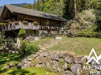 Charming wooden chalet nestled in a serene mountain setting, featuring a picturesque balcony adorned with flowers and intricate woodwork.