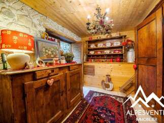 Step into a charming rustic kitchen featuring a vintage wooden sideboard adorned with decorative items and a floral lamp.