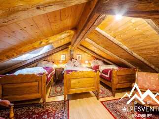Discover this charming attic bedroom featuring three rustic wooden beds, perfect for accommodating family or guests.