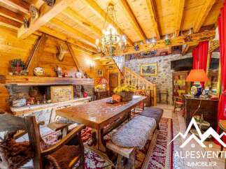 Experience rustic charm in this inviting dining area, featuring a grand stone fireplace and a large wooden table perfect for gatherings.