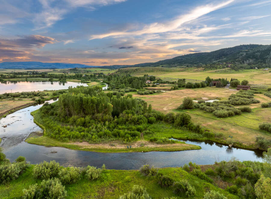 Discover this stunning rural property featuring a serene river winding through lush green landscapes and mature trees.