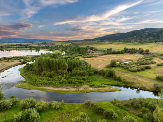 Discover this stunning rural property featuring a serene river winding through lush green landscapes and mature trees.