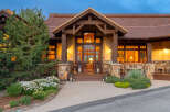 Experience luxury mountain living in this stunning lodge-style home, featuring a grand entrance with a rustic wooden door and arched glass.