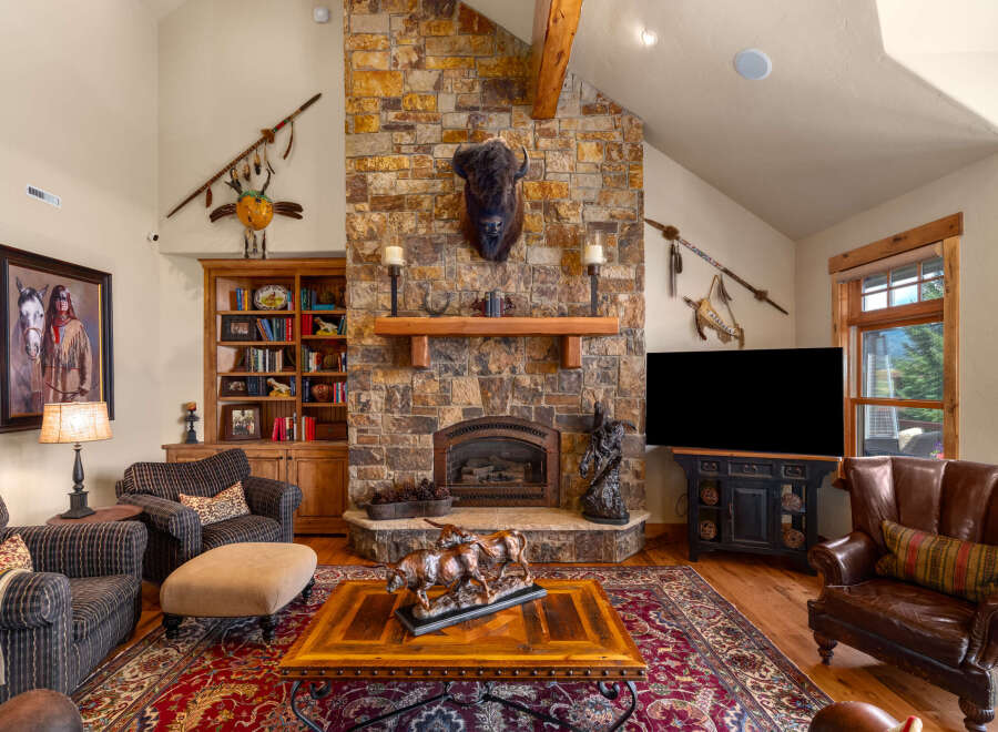 Experience rustic elegance in this stunning living room, featuring a grand stone fireplace as the centerpiece.