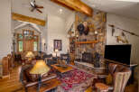 Experience rustic elegance in this spacious living room, featuring a grand stone fireplace adorned with a majestic bison head and Native American artifacts.