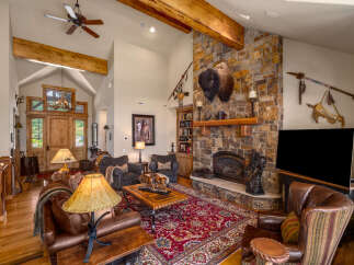 Experience rustic elegance in this spacious living room, featuring a grand stone fireplace adorned with a majestic bison head and Native American artifacts.