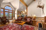 Experience rustic elegance in this spacious living room, featuring a grand arched window with stunning mountain views and exposed wooden beams.