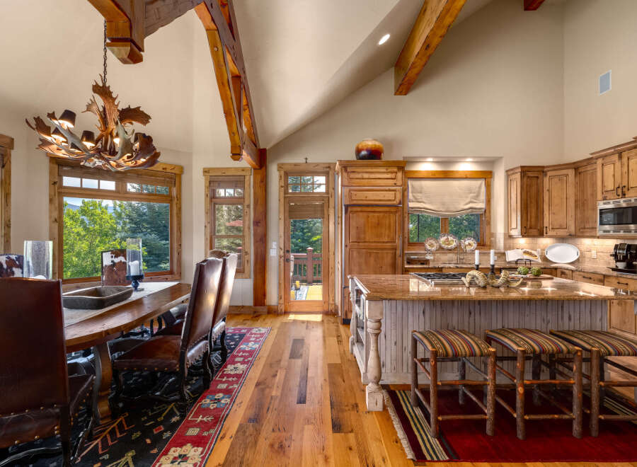 Experience rustic elegance in this stunning mountain home, featuring a grand dining area with a unique antler chandelier and leather seating.