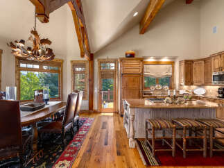 Experience rustic elegance in this stunning mountain home, featuring a grand dining area with a unique antler chandelier and leather seating.