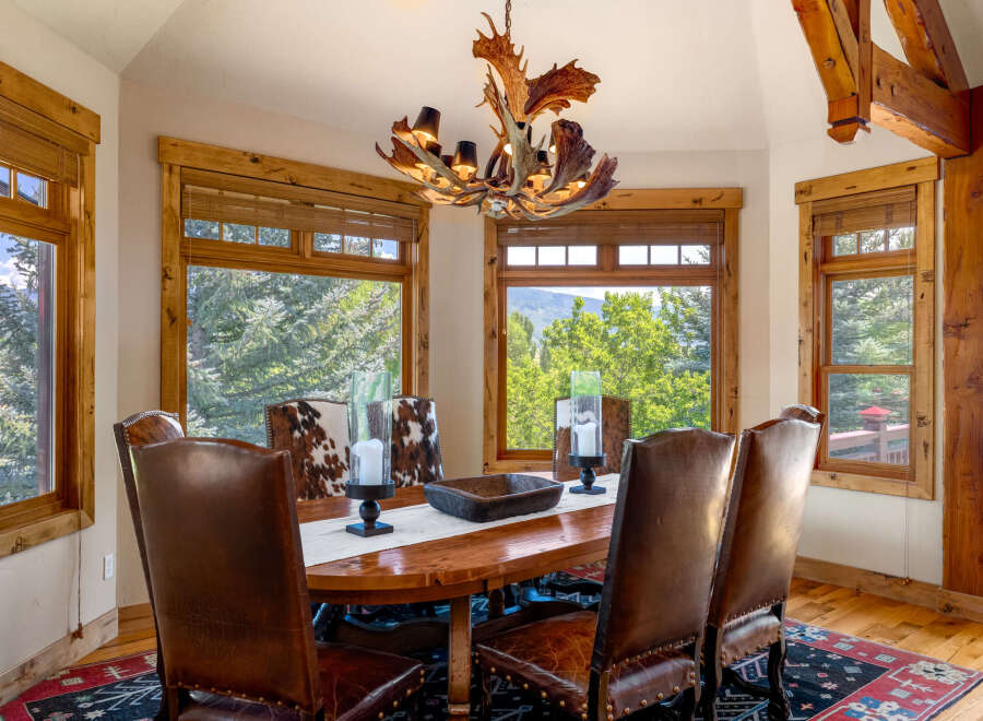 Experience rustic elegance in this stunning dining room, featuring a grand wooden table and plush leather chairs perfect for hosting.