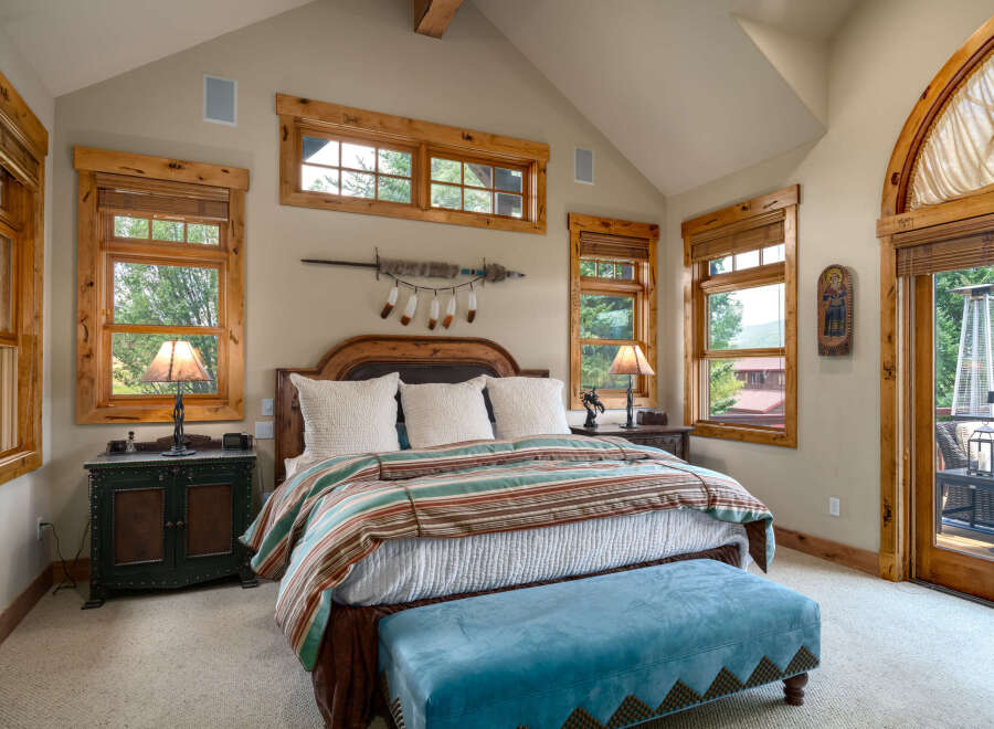 Experience rustic charm in this inviting bedroom, featuring a luxurious king-sized bed adorned with a striped comforter and plush pillows.