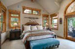 Experience rustic charm in this inviting bedroom, featuring a luxurious king-sized bed adorned with a striped comforter and plush pillows.