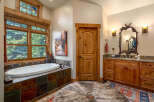 Indulge in relaxation in this luxurious bathroom featuring a deep soaking tub with stunning forest views through large wooden-framed windows.
