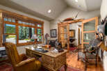 This rustic office space features a large wooden desk with a leather chair and a decorative rug.