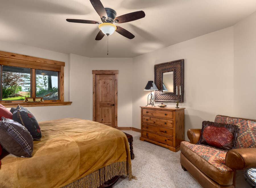 Experience rustic charm in this inviting bedroom, featuring a plush bed adorned with a suede-like throw and decorative pillows.