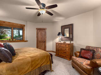 Experience rustic charm in this inviting bedroom, featuring a plush bed adorned with a suede-like throw and decorative pillows.